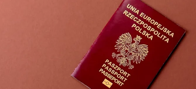Bordowy paszport ze znakiem orła, na terakotowym tle, potwierdzający obywatelstwo polskie