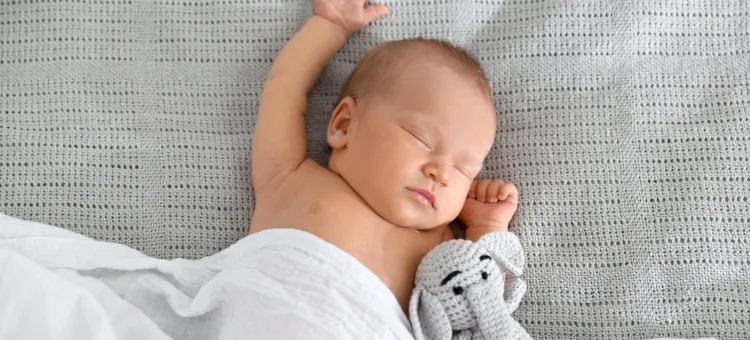 Spokojna drzemka niemowlęcia z pluszowym słonikiem na jasnym tle