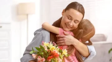 Rodzinne objęcie matki i dziewczynki, pełne ciepła i różnokolorowych kwiatów, na jasnym domowym tle