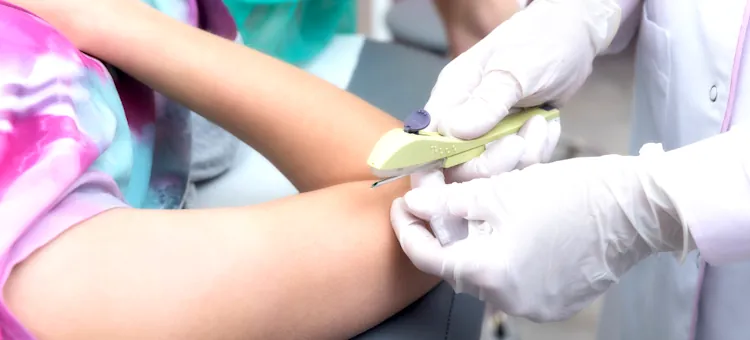 Jak przebiega założenie implantu antykoncepcyjnego? Lekarz w białych rękawiczkach wykonuje założenie implantu antykoncepcyjnego w zgięcie łokcia pacjentki na jasnym tle gabinetu,
