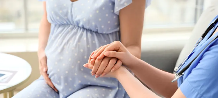 Wsparcie medyczne udzielane przyszłej mamie podczas wizyty w gabinecie lekarskim, zbliżenie na ręce lekarki, trzymające ręce pacjentki