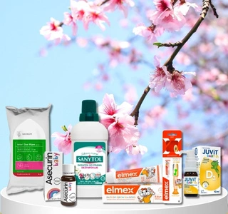Produkty Sanytol, Asecurin baby, elmex®, Velox Duo Wipes i Juvit Baby D3 na tle kwitnących różowych gałęzi