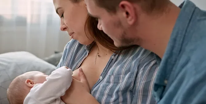 Czuły tata wspiera partnerkę podczas karmienia piersią noworodka w jasnej sypialni