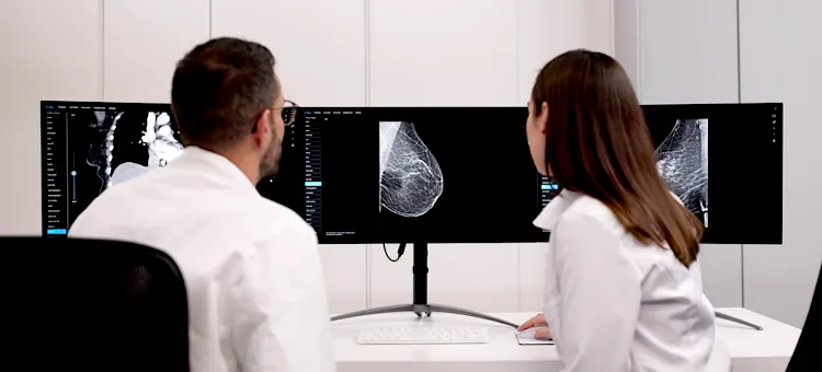 Specjaliści medyczni sprawdzają cyfrowe zdjęcia mammograficzne na monitorach w jasnym gabinecie diagnostycznym